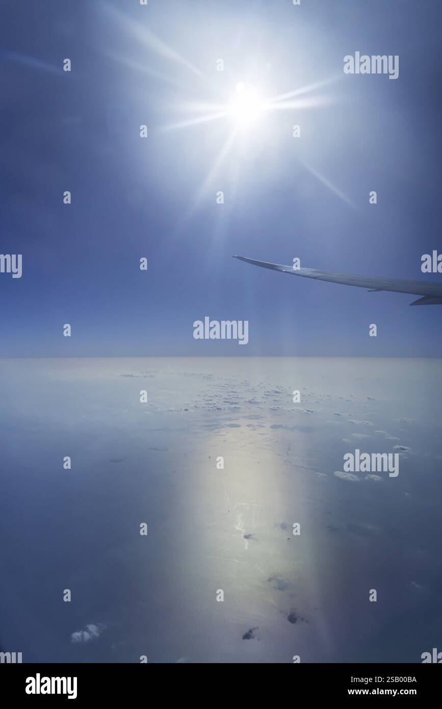 Vista del Golfo Persico dalla finestra dell'aereo. Sole e nuvole sul mare. Volo con la compagnia aerea Etihad. Abu Dhabi, Emirati Arabi Uniti, Emirati Arabi Uniti Foto Stock