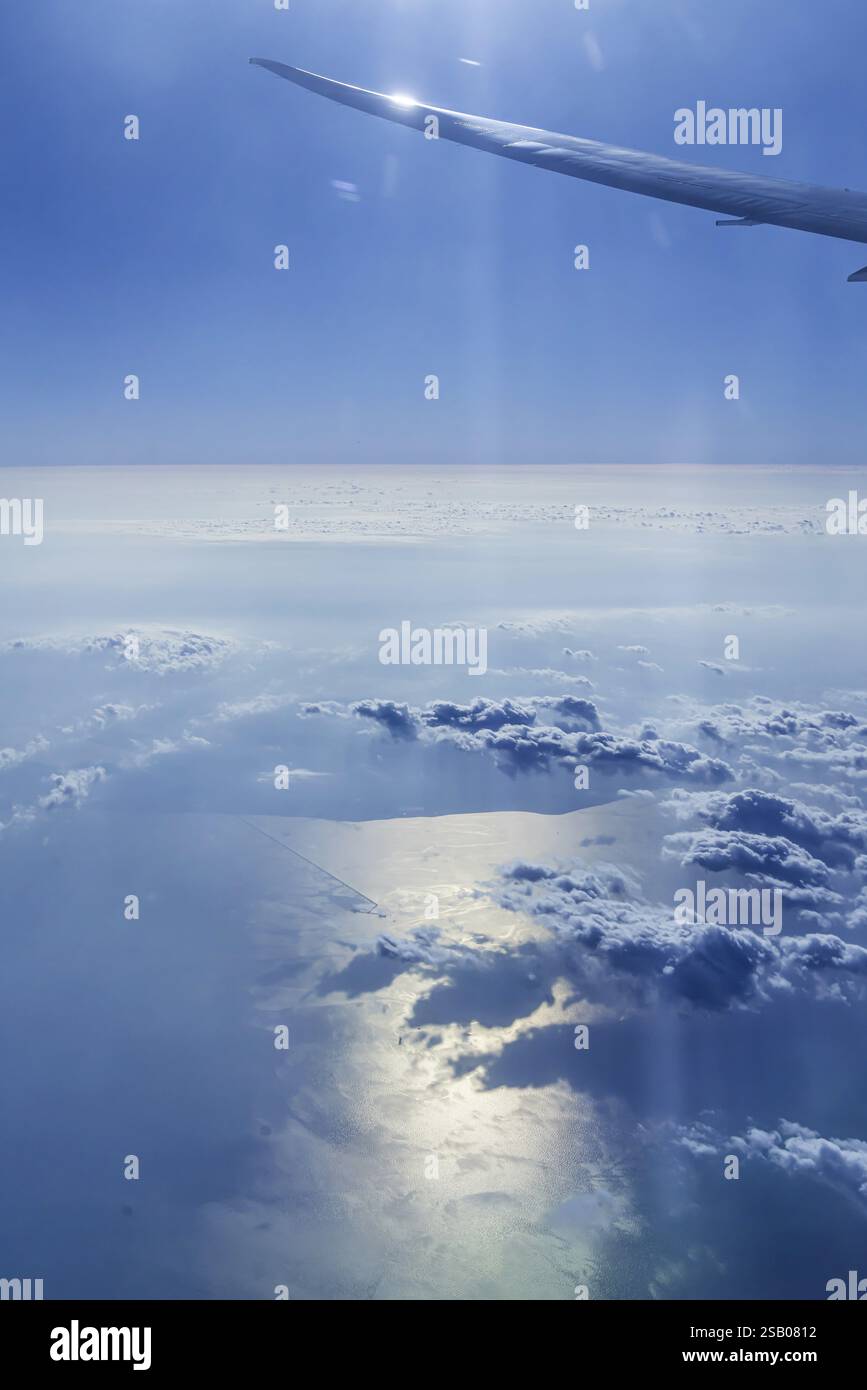Vista del Golfo Persico dalla finestra dell'aereo. Sole e nuvole sul mare. Volo con la compagnia aerea Etihad. Abu Dhabi, Emirati Arabi Uniti, Emirati Arabi Uniti Foto Stock