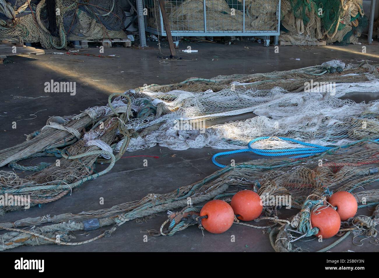 Un hangar di pescatori con reti e attrezzi da pesca disposti in modo ordinato. L'area coperta fornisce uno spazio di lavoro per la manutenzione della rete, essenziale per i pesci locali Foto Stock