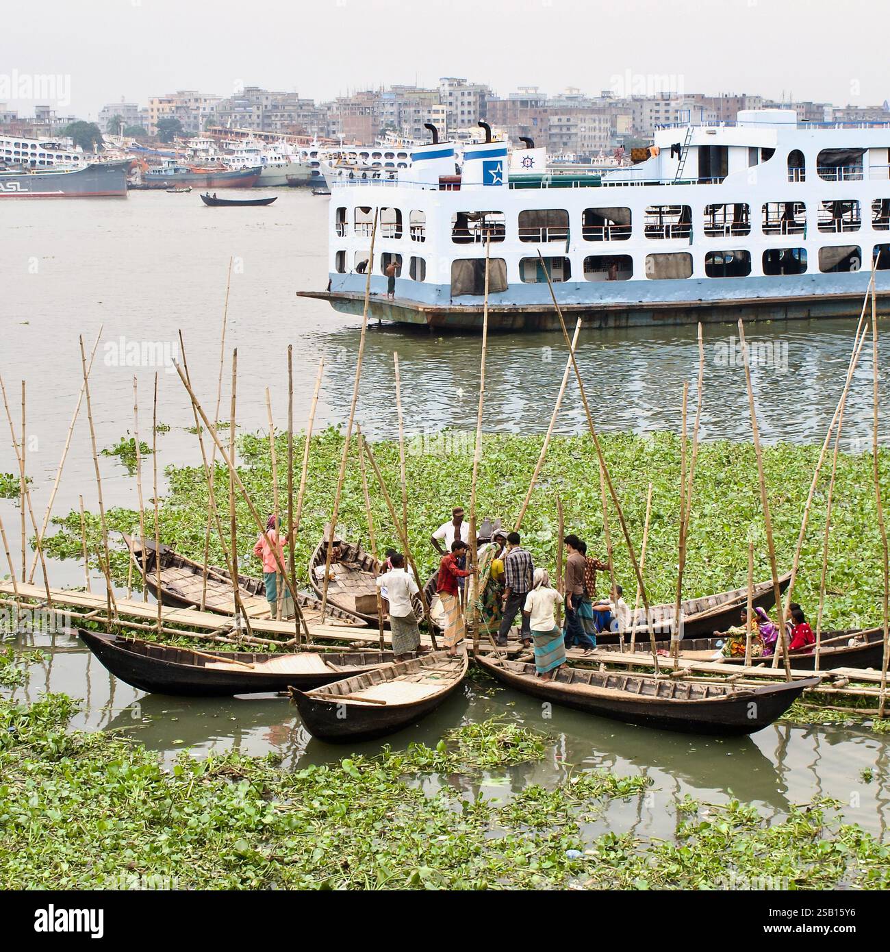 Barche in legno trasportano passeggeri attraverso il fiume Buriganga a Dacca, Bangladesh, con un grande traghetto passeggeri e lo skyline urbano sullo sfondo. Foto Stock