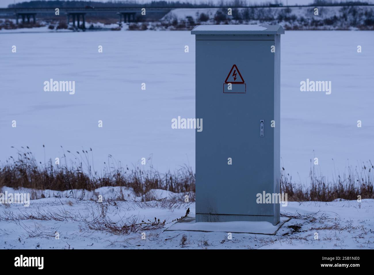 Scatola elettrica sulla riva del fiume ghiacciata in inverno Foto Stock