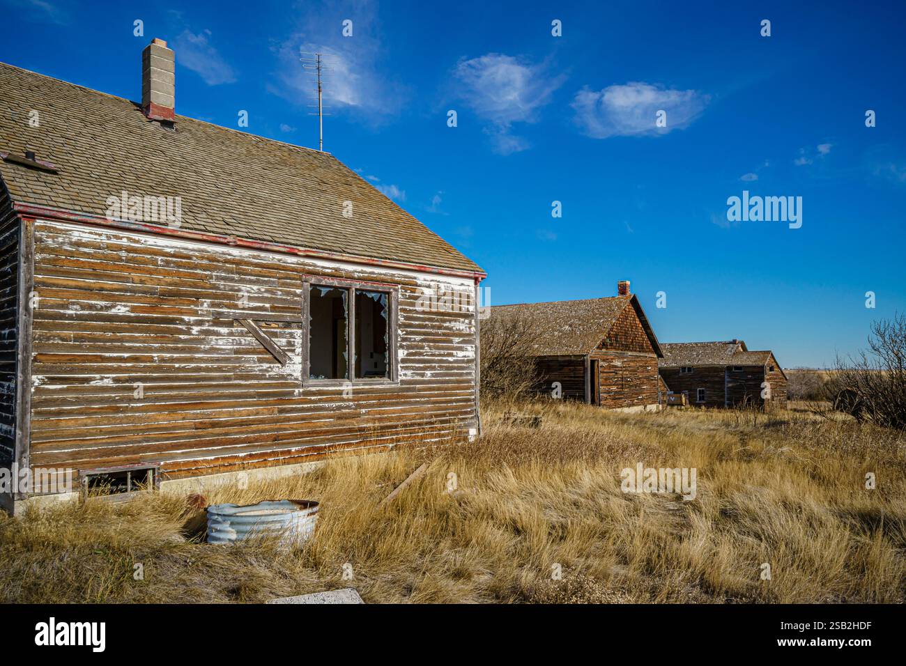 Una casa con un camino e un secchio di metallo a terra. La casa è vecchia e ha molto legno Foto Stock