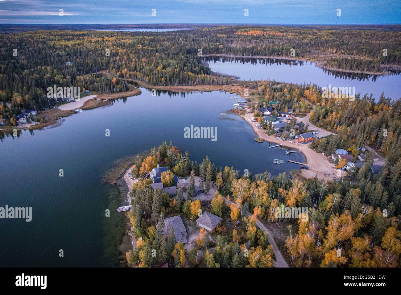 Un lago con una città sulla riva. La città è circondata da alberi. Il lago è pieno di barche Foto Stock