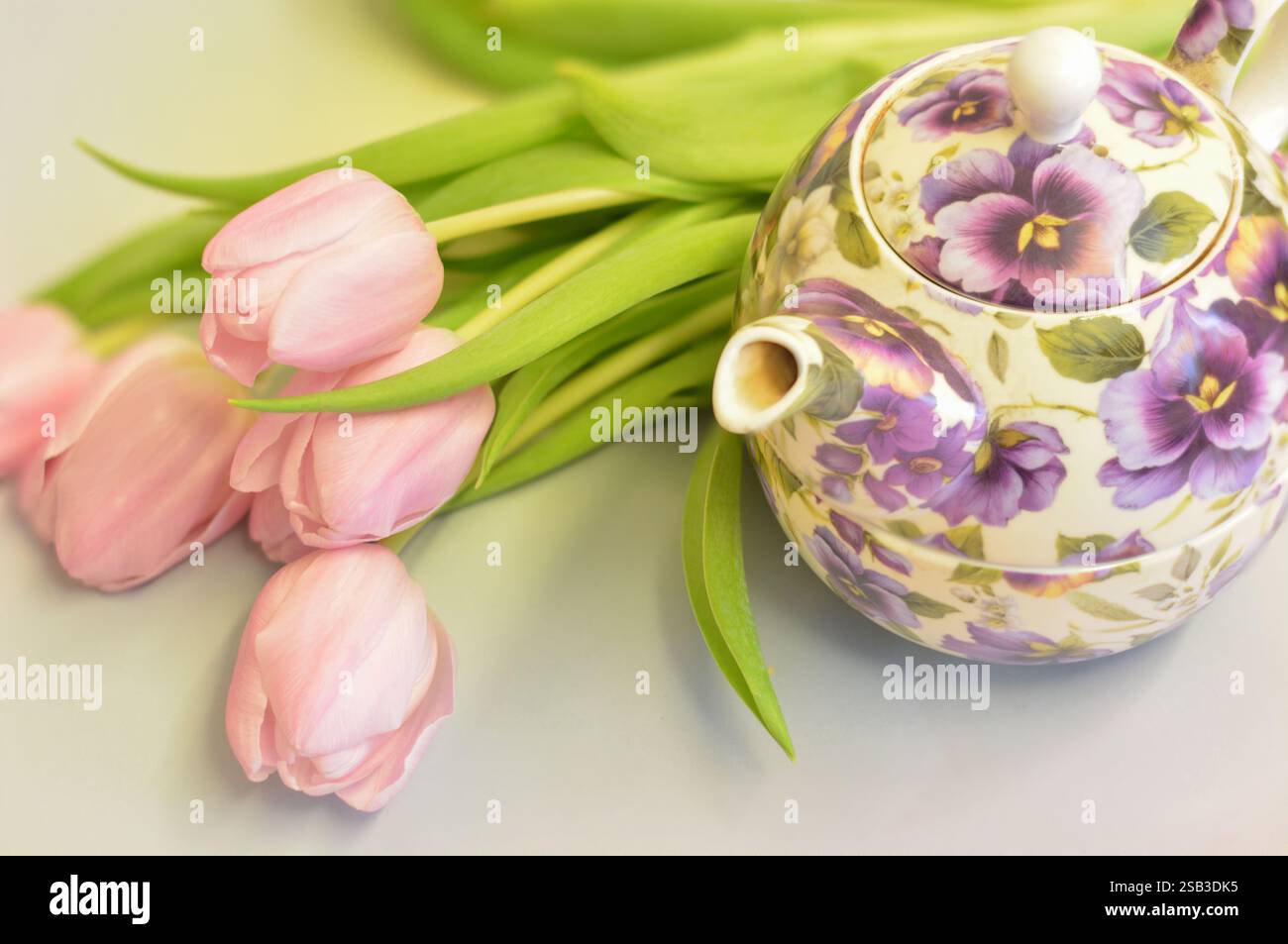 Teiera floreale e tulipani rosa per il tè di Pasqua e del pomeriggio; tè per una teiera. Concetto per Pasqua e bevitore di tè single lady. Foto Stock