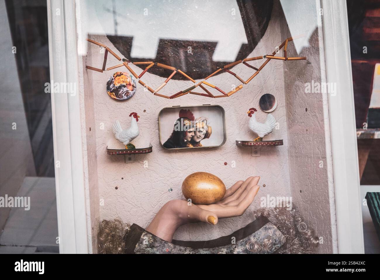 Opera d'arte astratta, una mano che regge un uovo d'oro, ritratto di due donne con i galli Foto Stock