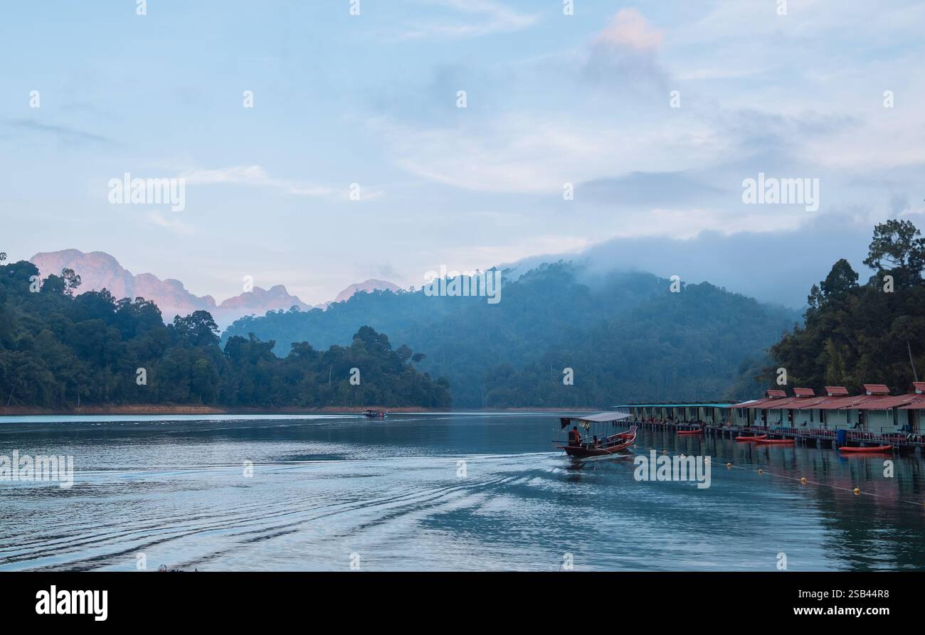 Capanne galleggianti del villaggio con vista incredibile del lago Cheow LAN, circondate dalla giungla della foresta pluviale e dalle nuvole serali. Panorama mozzafiato a Surat Thani Prov Foto Stock