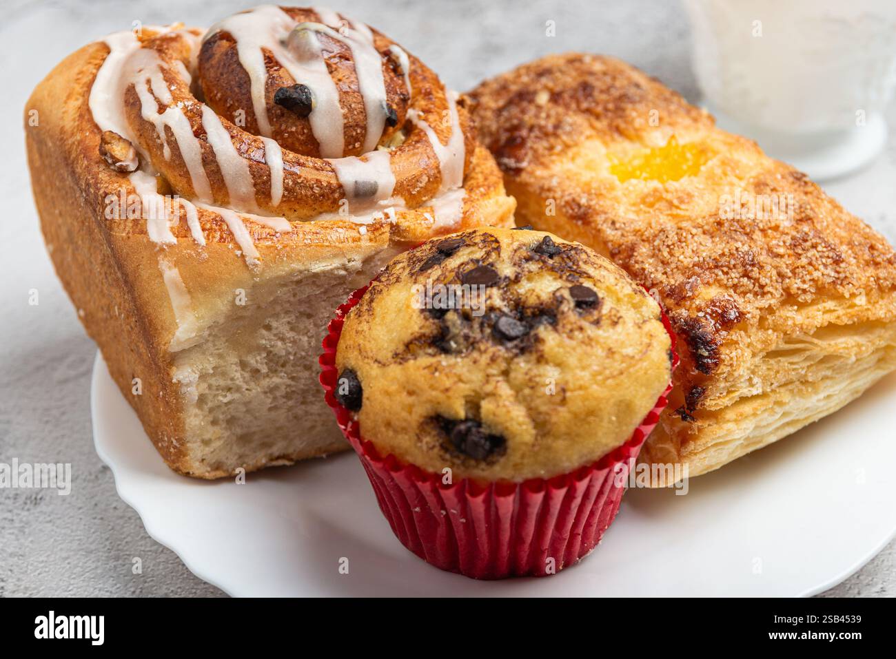 Primo piano di un piatto bianco con diversi dessert appena sfornati, dolci alla cannella, cupcake e un dolce dolce. Foto Stock