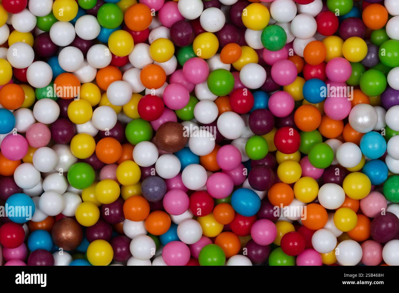 Sfondo multicolore con perline di zucchero: Vivace motivo arcobaleno di colorate stampe rotonde e decorazioni di perle bianche per torta e dessert Foto Stock