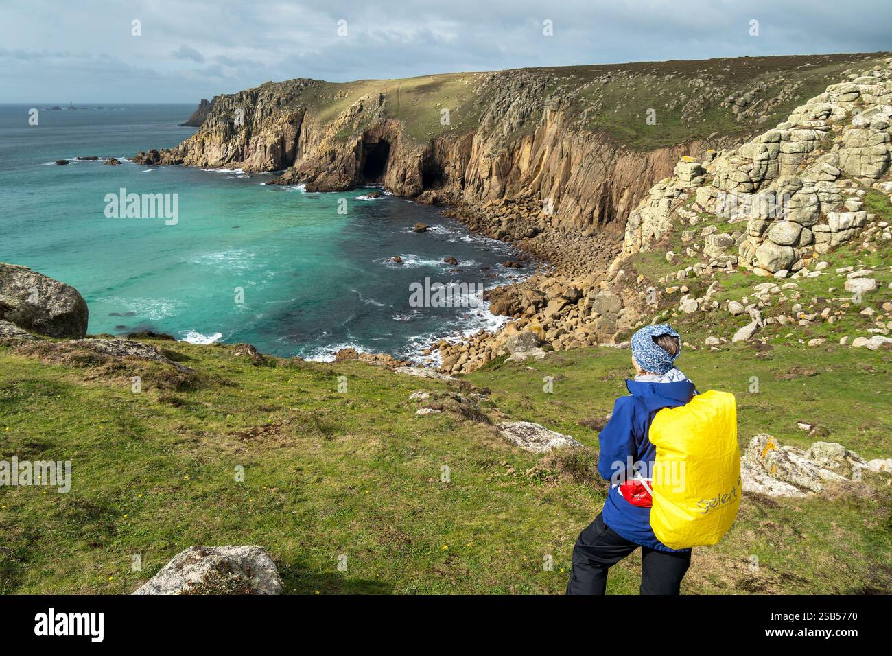 Turista sopra scogliere rocciose e costa sul sentiero costiero della Cornovaglia meridionale vicino a Pendower Coves, Cornovaglia, Inghilterra, Regno Unito Foto Stock