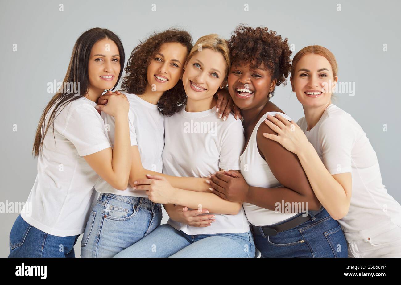Giovani donne felici e diverse che guardano la telecamera isolata su sfondo grigio studio. Foto Stock