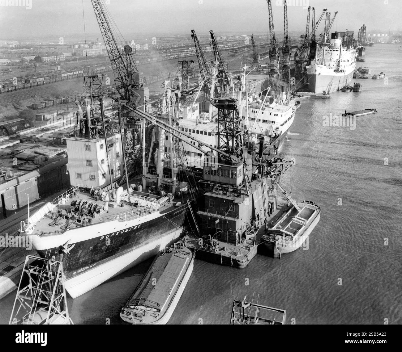 Una scena movimentata al porto di Hull, Kingston upon Hull, East Yorkshire, Inghilterra, Regno Unito nel 1957. Qui una nave da carico scarica il grano nelle chiatte per mezzo di un elevatore per cereali al molo numero 1 al molo King George. Il porto di Hull si trova alla confluenza del fiume Hull e dell'estuario dell'Humber. Le chiatte grandi, larghe e dalla parte anteriore piatta erano originariamente note come «Humber Keels». Foto Stock