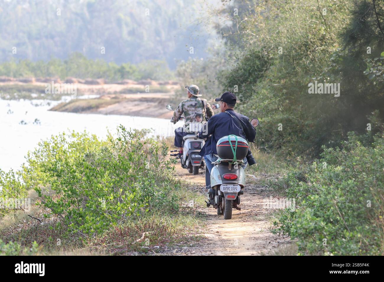 (250201) -- HAIKOU, 1 febbraio 2025 (Xinhua) -- Luo Lixiang (R) e il suo collega di pattuglia presso il parco nazionale delle paludi di Hainan Xinying Mangrove a Danzhou, provincia cinese meridionale di Hainan, 18 gennaio 2025. L'Hainan Xinying Mangrove National Wetland Park è stato fondato a Danzhou nel 2007 e Luo Lixiang è diventato il primo gruppo di ranger del parco, che ha assistito ai cambiamenti ecologici qui negli ultimi anni. Prima dell'istituzione del parco delle zone umide, la zona umida fu distrutta a causa di uno sviluppo acquacoltura improprio. Al fine di ripristinare il sistema ecologico, il governo locale ha lanciato Foto Stock