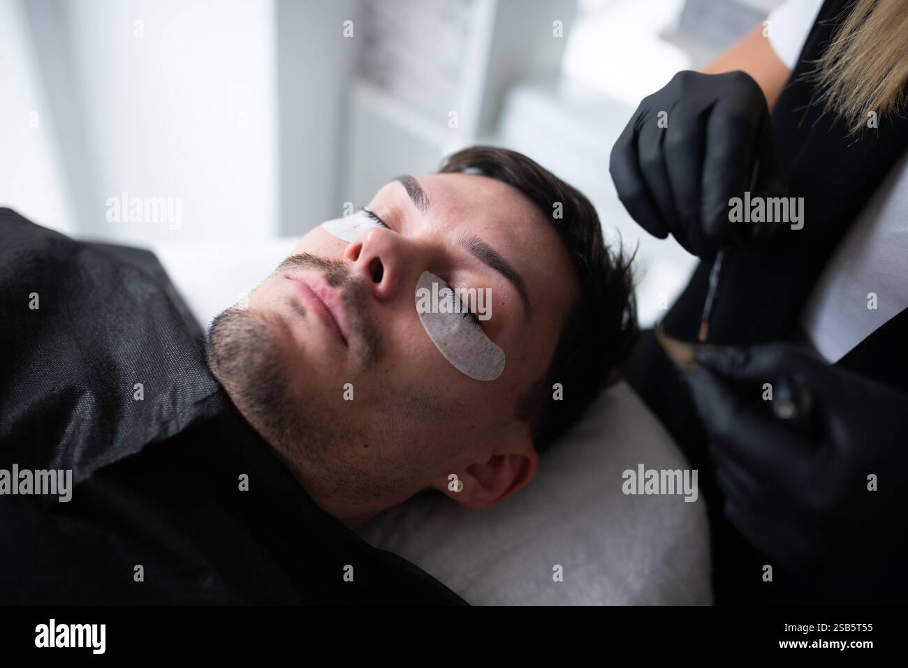 Un giovane in un salone di bellezza che si prende cura delle ciglia. Foto Stock