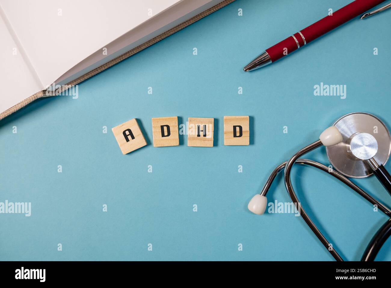 Blocco di legno con le lettere ADHD scritte su di esso. Sul tavolo sono presenti anche una penna e uno stetoscopio Foto Stock