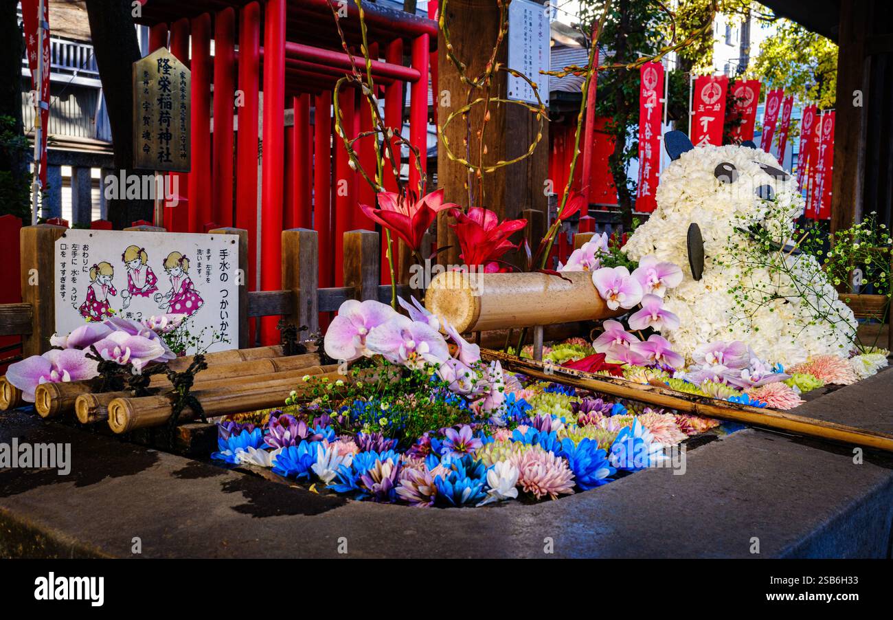 Il Santuario Shitaya a Higashi-Ueno, Taito Ward, Tokyo, presenta una fonte d'acqua splendidamente adornata, spesso decorata con fiori freschi. Il flor Foto Stock
