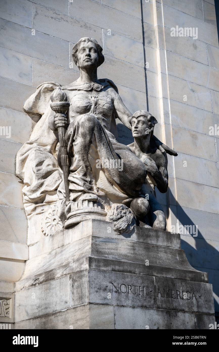 North America Sculpture Organization of American States Building Washington DC // WASHINGTON DC — la scultura allegorica in marmo "North America" di Gutzon Borglum si trova all'ingresso destro dell'Organization of American States Building. Creata nel 1910, la scultura raffigura una figura femminile drappeggiata che tiene in mano una torcia, accompagnata da un giovane vigile. La scultura si abbina al "Sud America" sul lato opposto, fiancheggiando le griglie d'ingresso in bronzo. Foto Stock