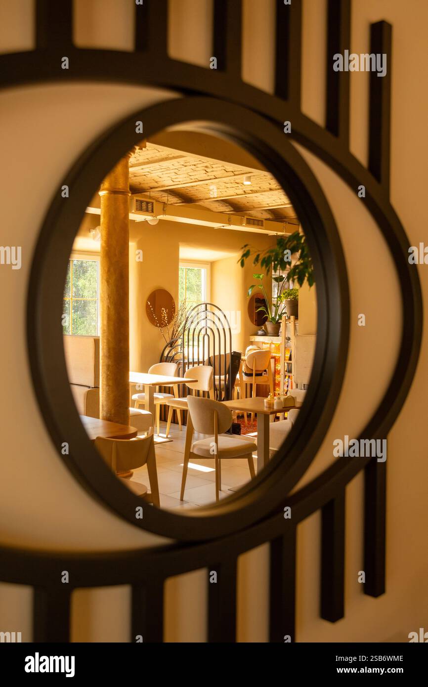 Gli invitanti interni di una caffetteria adornati con colori caldi e accoglienti mobili imbottiti, creano un'atmosfera perfetta per il relax e il caffè Foto Stock