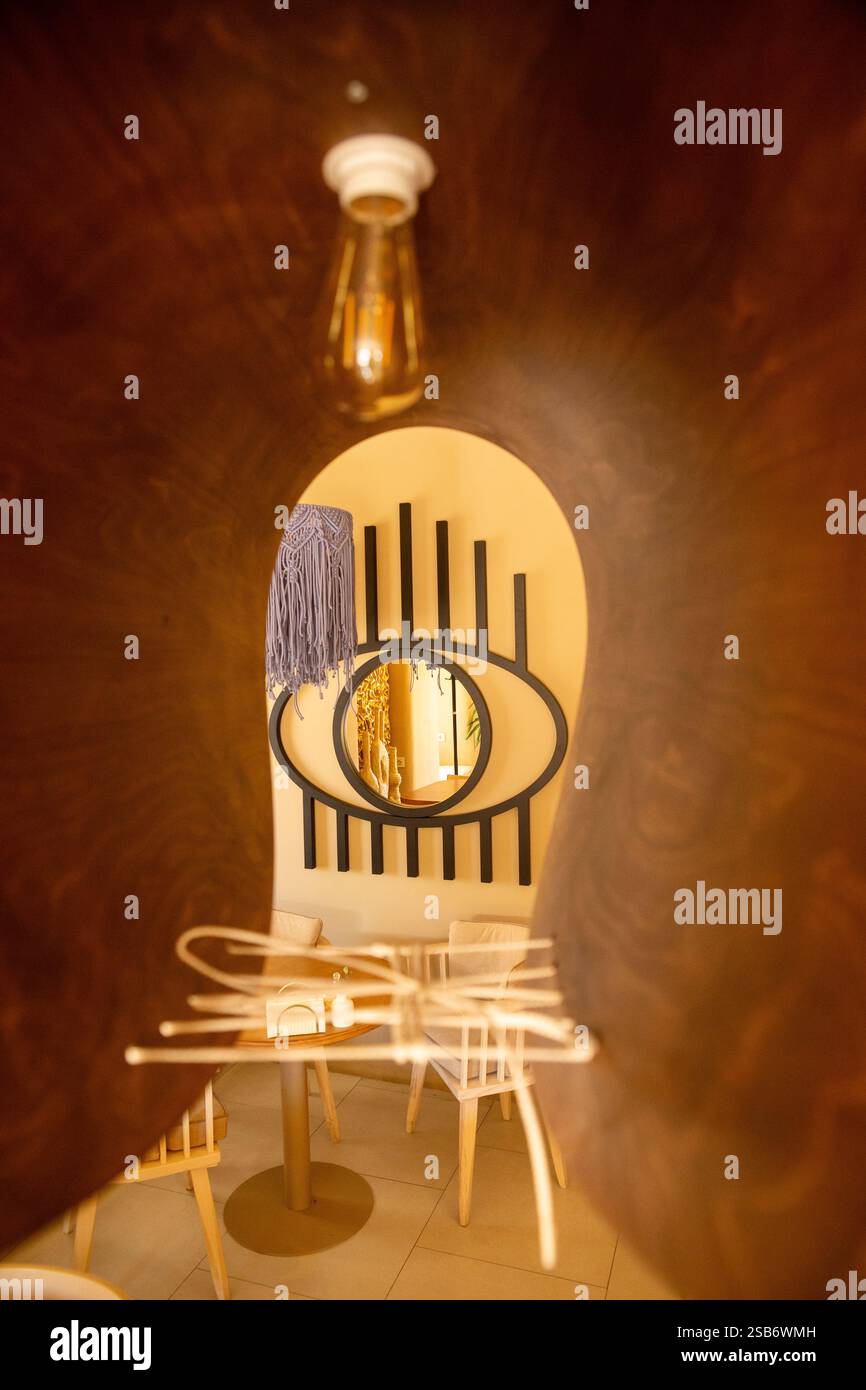 Gli invitanti interni di una caffetteria adornati con colori caldi e accoglienti mobili imbottiti, creano un'atmosfera perfetta per il relax e il caffè Foto Stock