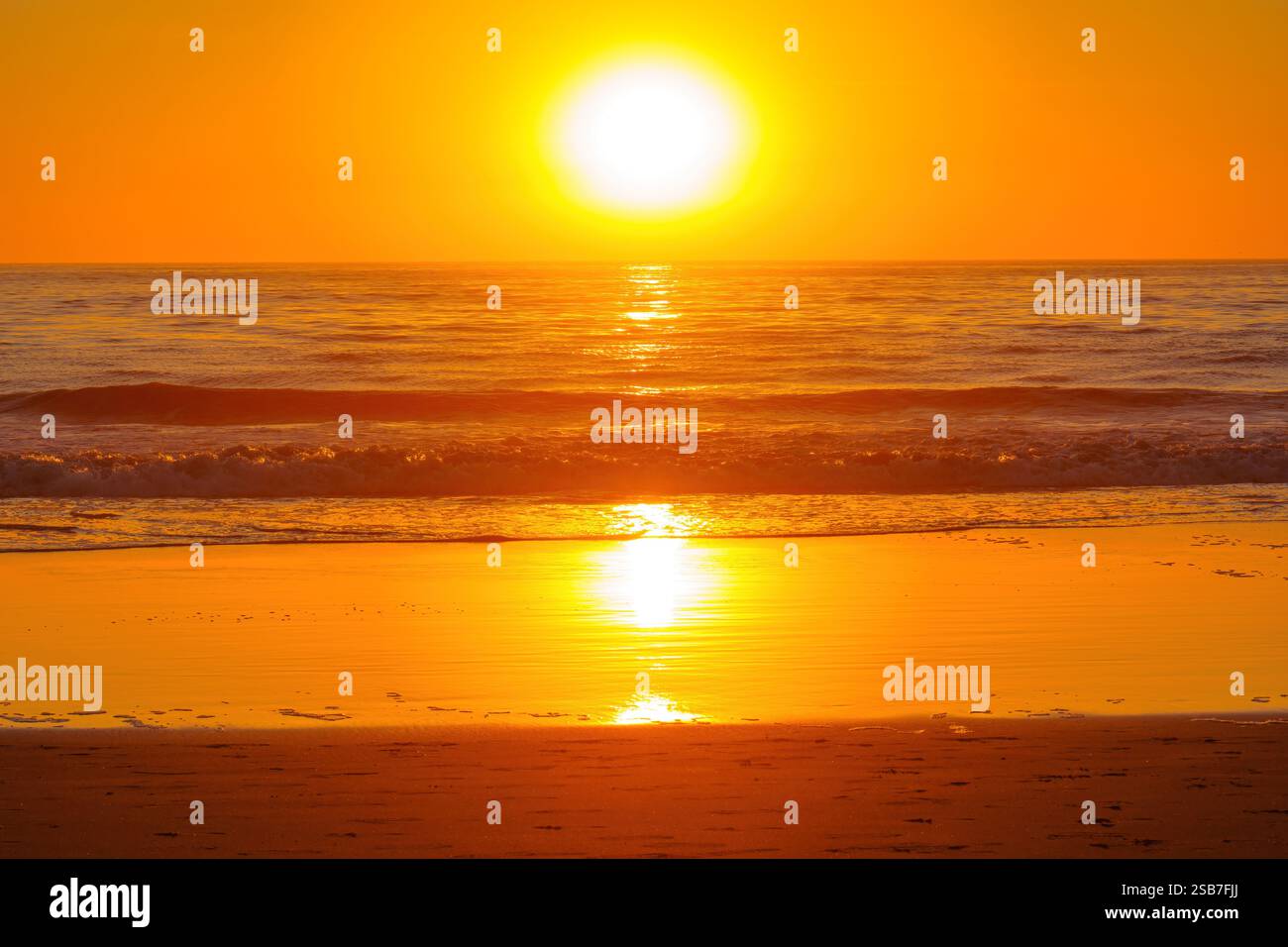 Il tramonto dorato mozzafiato proietta vivaci sfumature sulle onde dell'oceano a Venice Beach, creando un'atmosfera tranquilla. Foto Stock