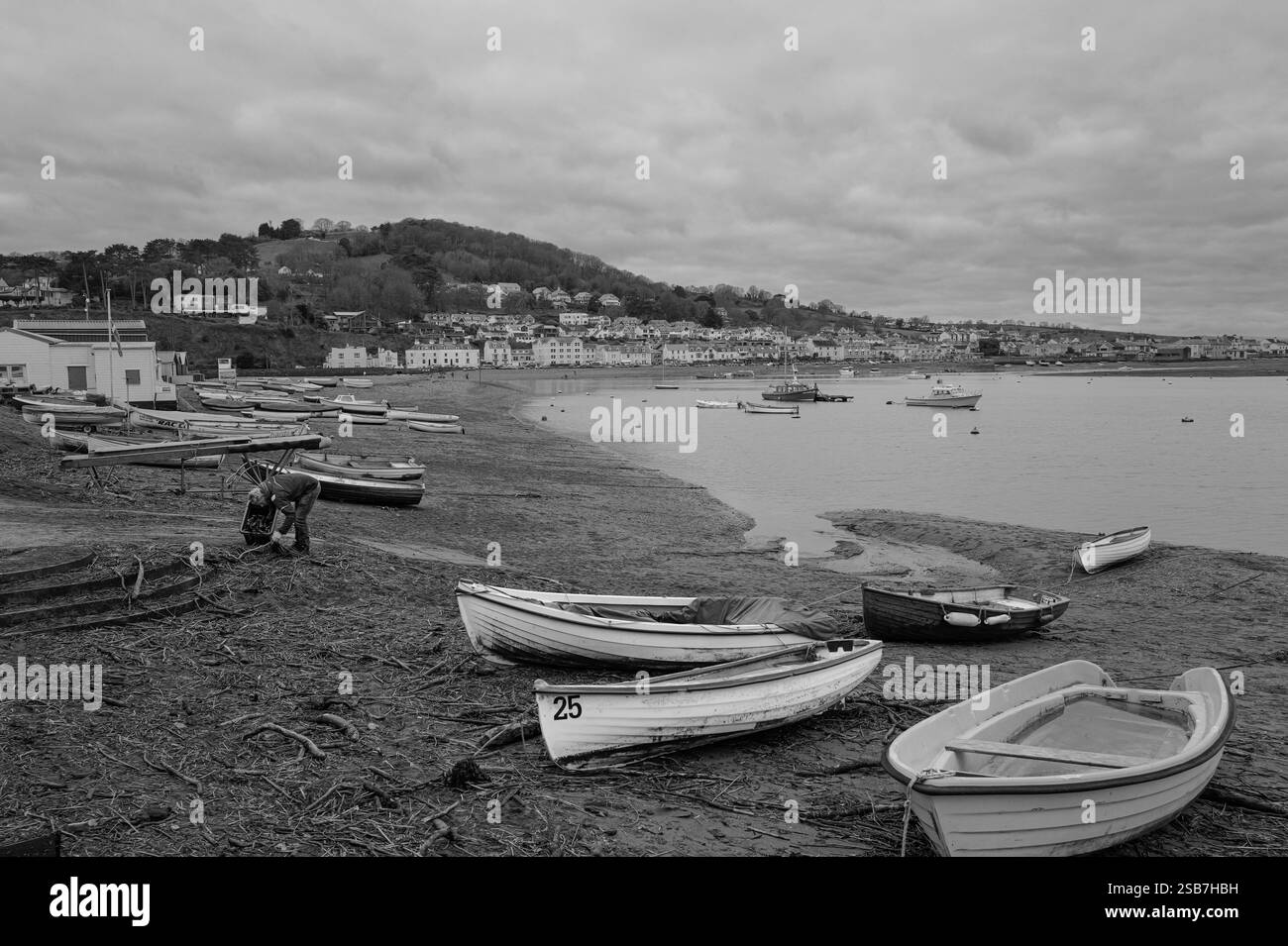 Uomo sulla spiaggia che svuota i detriti a Teignmouth, Devon, Inghilterra. Fotografia in bianco e nero. Foto Stock