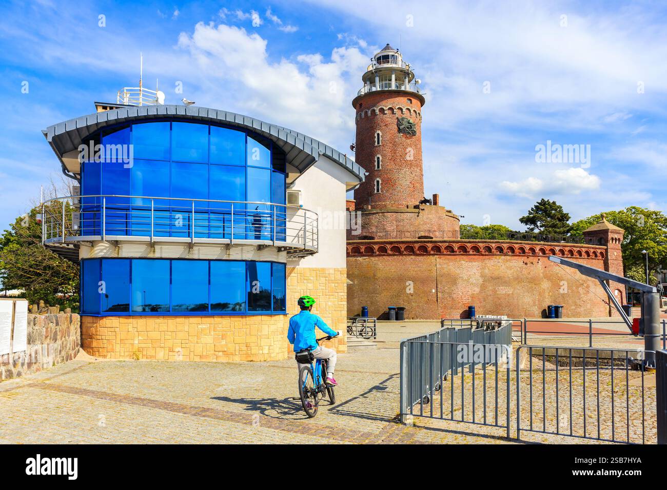 Giovane ciclista vicino alla torre del faro nel porto di Kolobrzeg, costa del Mar Baltico, Polonia Foto Stock
