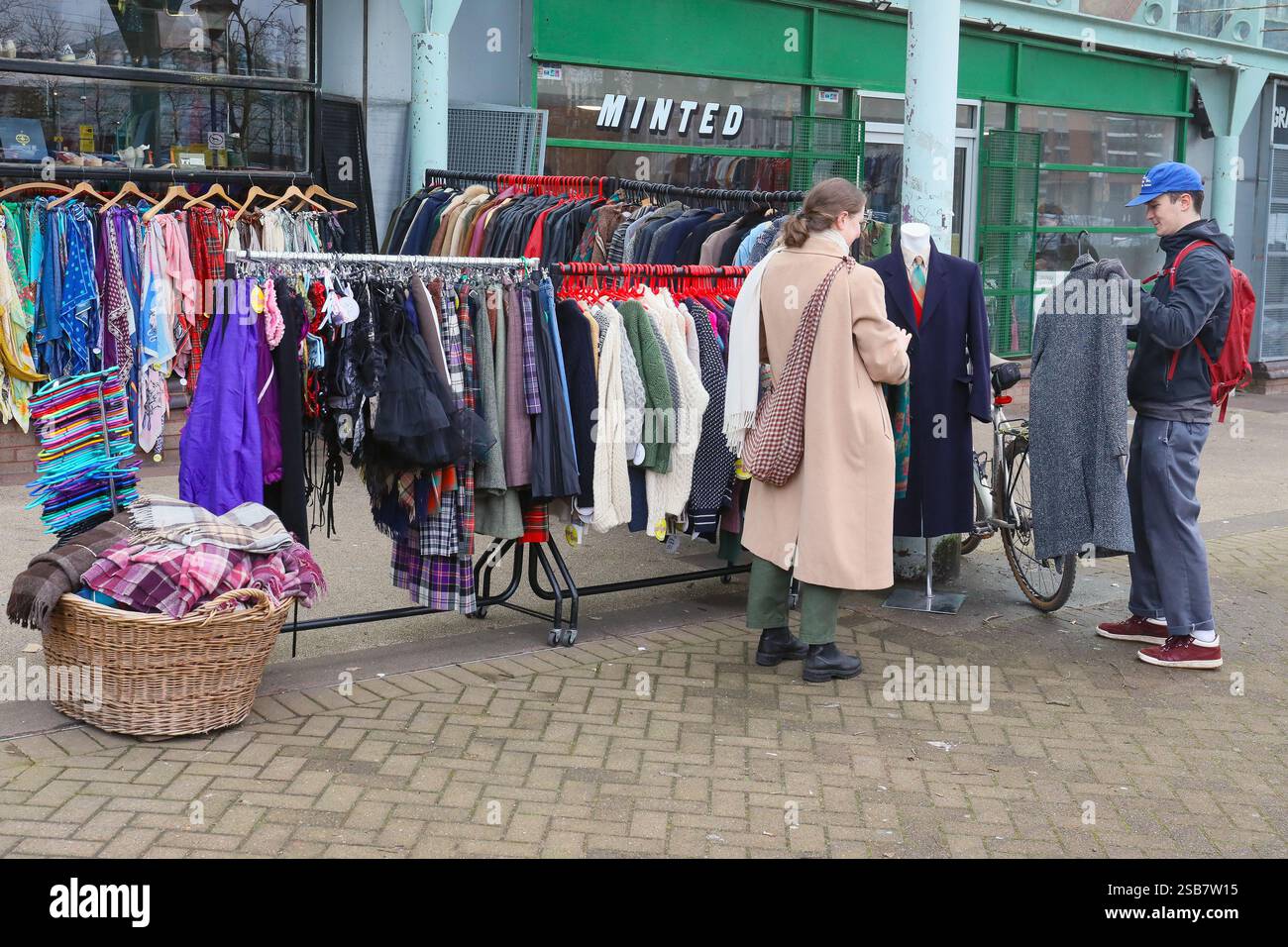 Uomo e donna in cerca di vestiti da una boutique di seconda mano, Glasgow, Scozia, Regno Unito Foto Stock