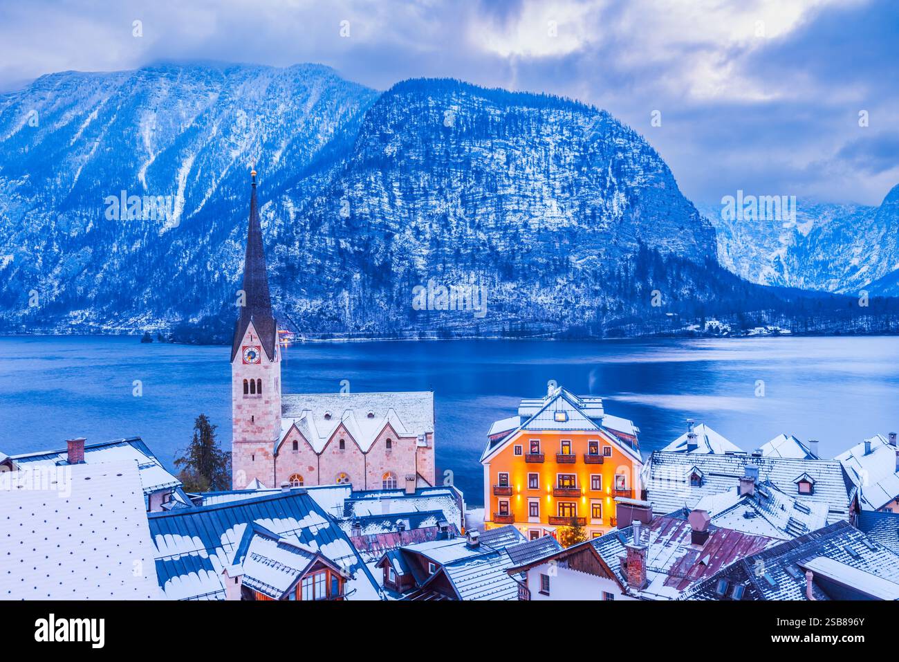 Hallstatt, Austria - Snowy crepuscolo invernale di tranquillo villaggio alpino, tetti innevati, lago sereno, montagne maestose. Foto Stock