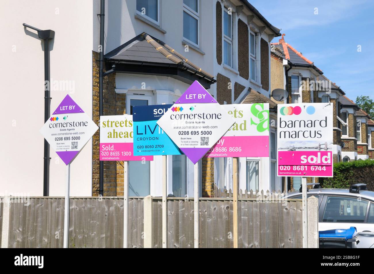 Una fila di agenti immobiliari ha lasciato passare e venduto cartelli inchiodati a una recinzione vicino alla proprietà nella grande Londra, Inghilterra, Regno Unito. cartelli per il noleggio di abitazioni Foto Stock