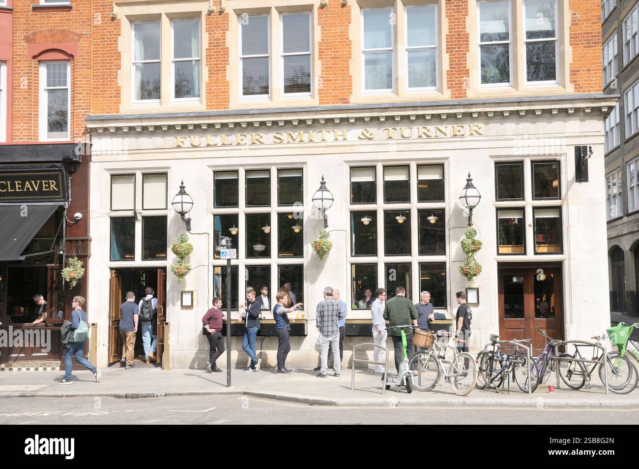 Persone che bevono sul marciapiede fuori dal Butchers Hook and Cleaver, un pub Fuller Smith and Turner vicino a Smithfield, City of London, Inghilterra, Regno Unito Foto Stock