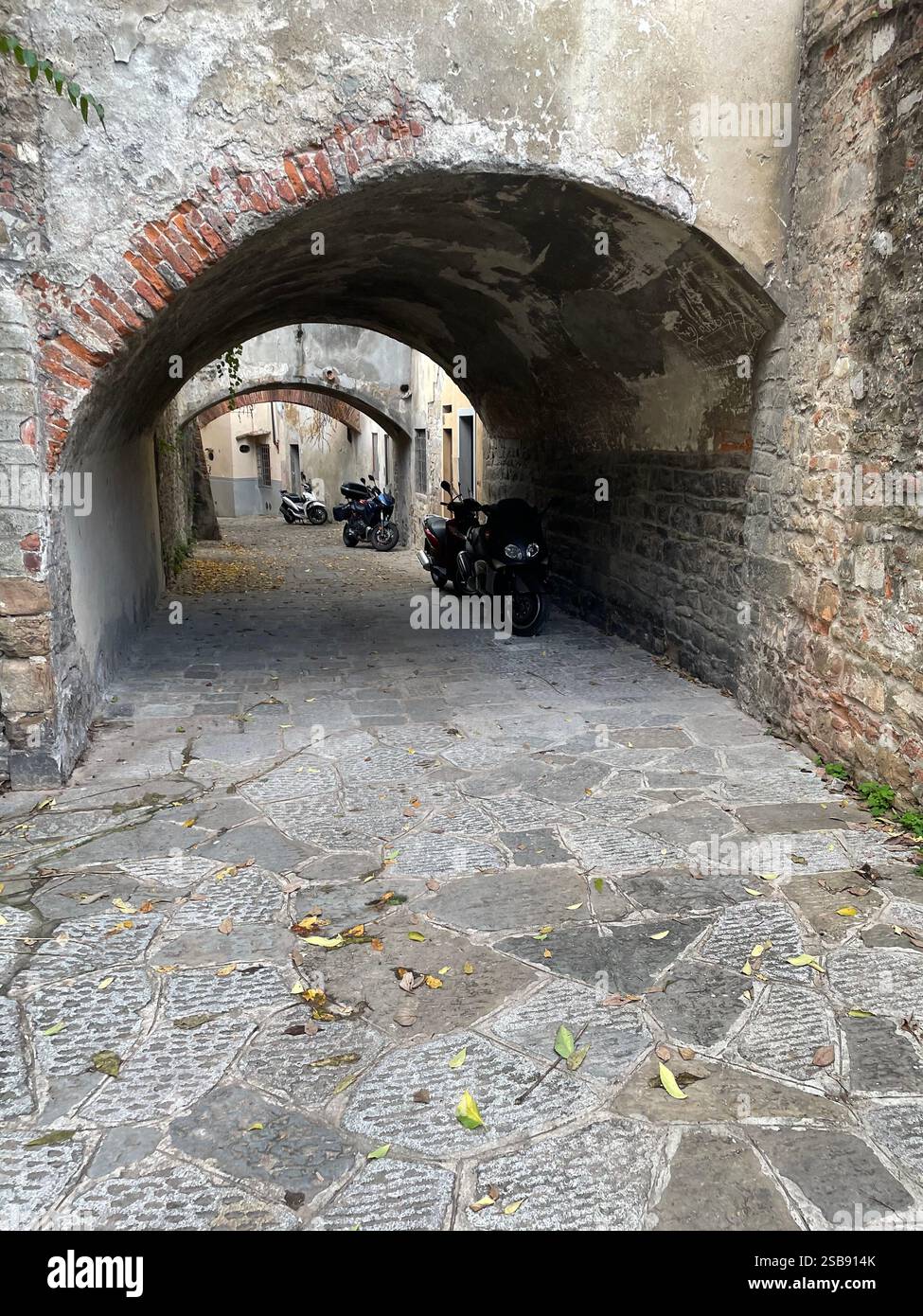 Scooter parcheggiati in passaggi sotto vecchi edifici nel centro storico di Firenze - Immagine stock catturata con smartphone