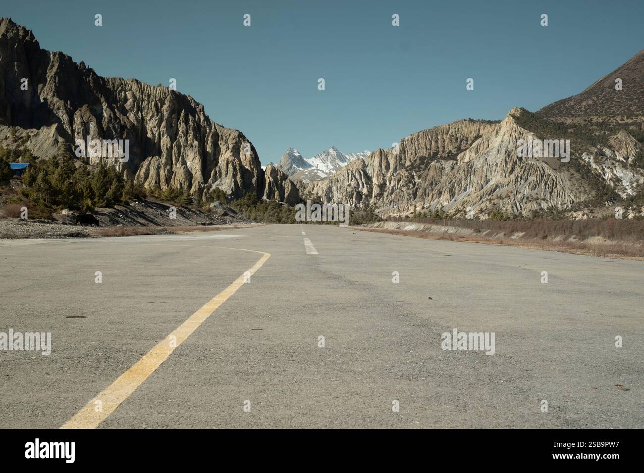 Una pista vuota all'aeroporto di Humde, incorniciata dalla splendida catena dell'Annapurna, un punto di ingresso alla maestosa natura selvaggia. Foto Stock