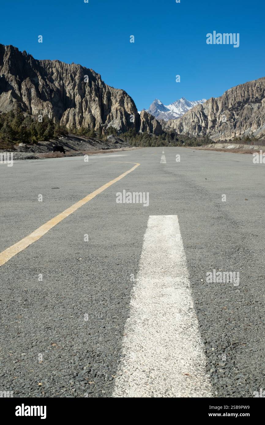Una pista vuota all'aeroporto di Humde, incorniciata dalla splendida catena dell'Annapurna, un punto di ingresso alla maestosa natura selvaggia. Foto Stock