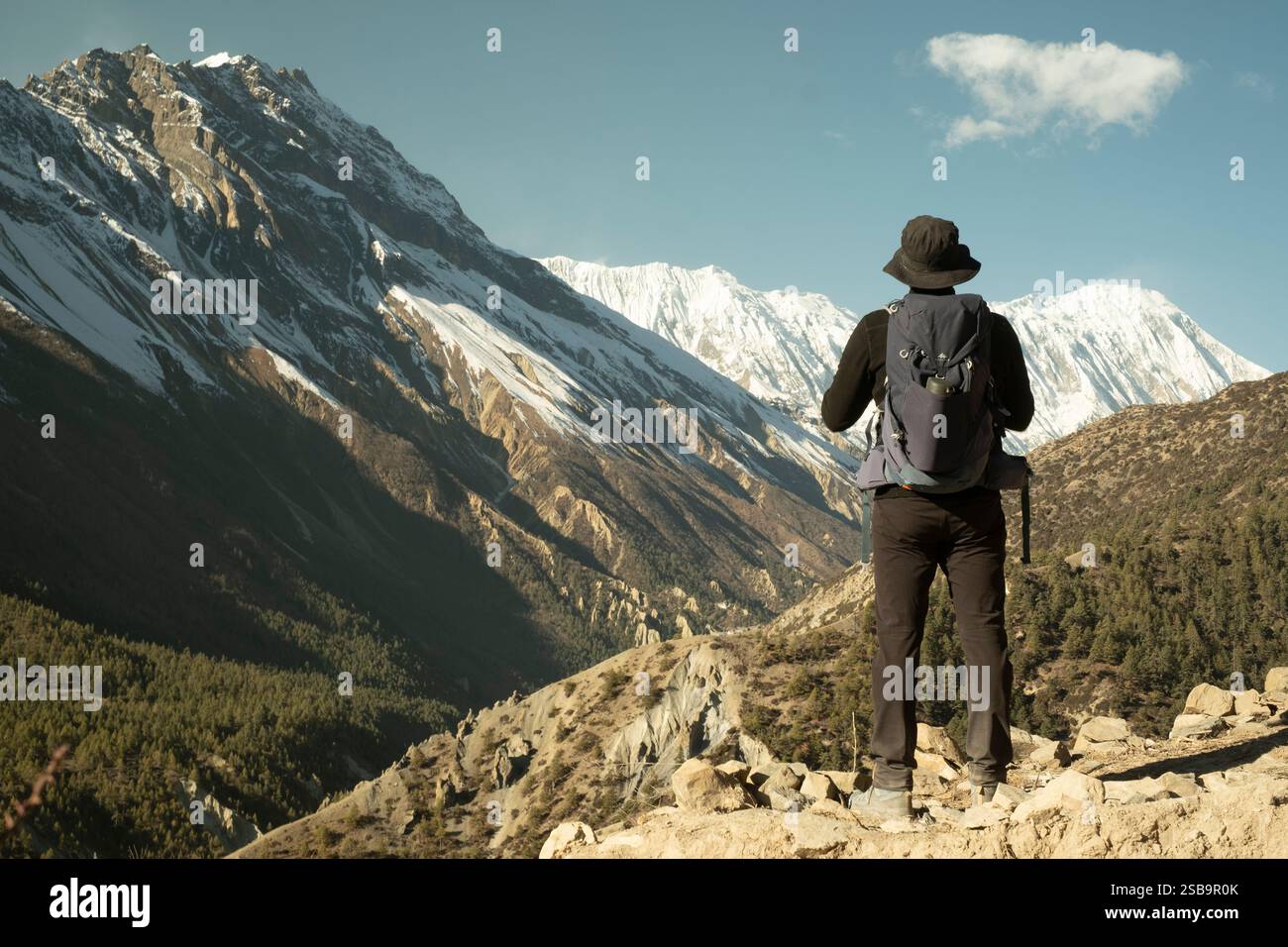 Un escursionista si diverte nelle viste mozzafiato delle montagne in una giornata d'inverno limpida, abbracciando la tranquillità e la bellezza dell'Himalaya. Foto Stock