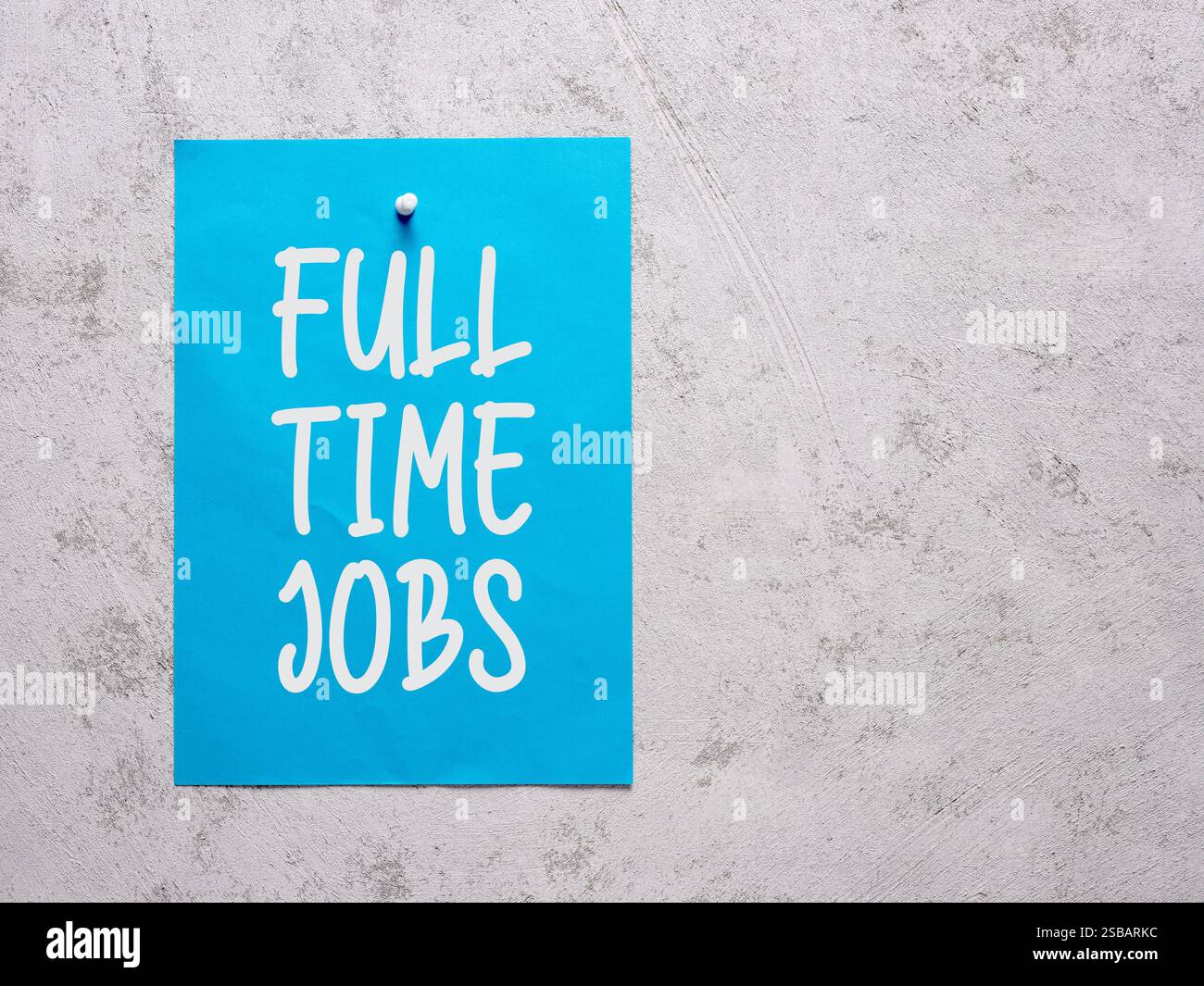 Annuncio dei lavori a tempo pieno su un foglio di carta blu fissato a una parete bianca di cemento. Impiego aziendale e pubblicità di reclutamento. Foto Stock