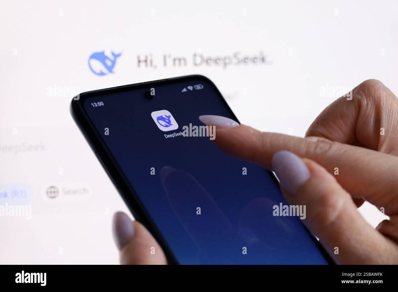 Logo Deepseek ai sul display del computer e sullo schermo dello smartphone con una mano femminile Foto Stock