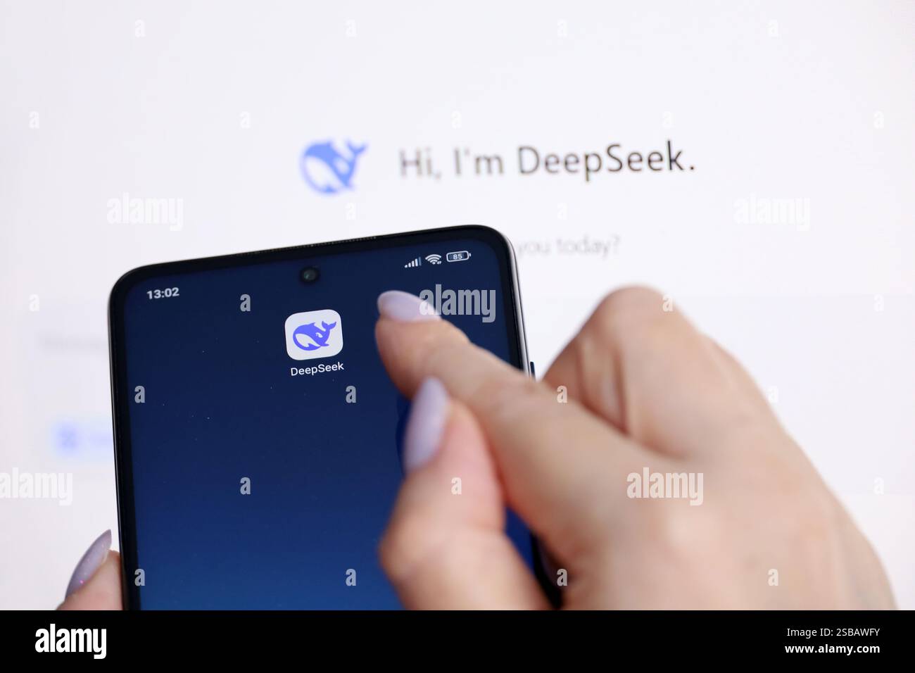 Logo Deepseek ai sul display del computer e sullo schermo dello smartphone con una mano femminile Foto Stock