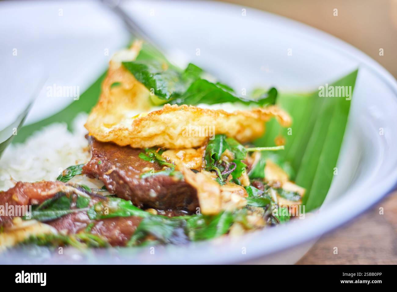 Pad Kra Pao. Frittura in padella di manzo di basilico in stile tailandese con uova fritte. Menu di piatti thailandesi Foto Stock