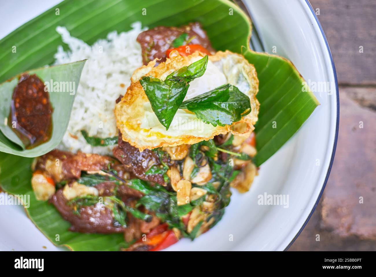 Pad Kra Pao. Frittura in padella di manzo di basilico in stile tailandese con uova fritte. Menu di piatti thailandesi Foto Stock