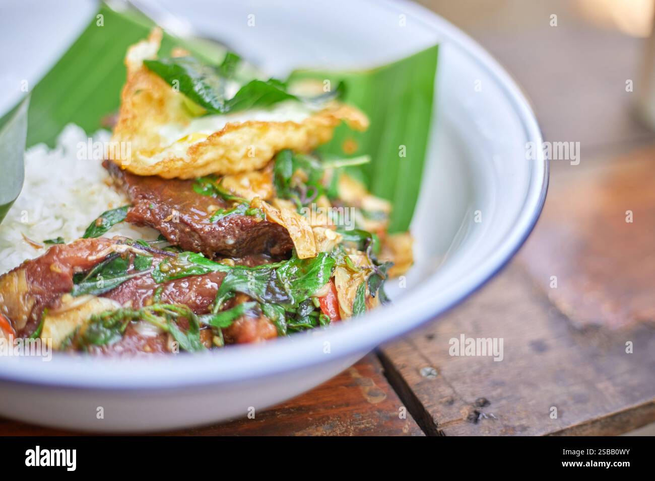 Pad Kra Pao. Frittura in padella di manzo di basilico in stile tailandese con uova fritte. Menu di piatti thailandesi Foto Stock