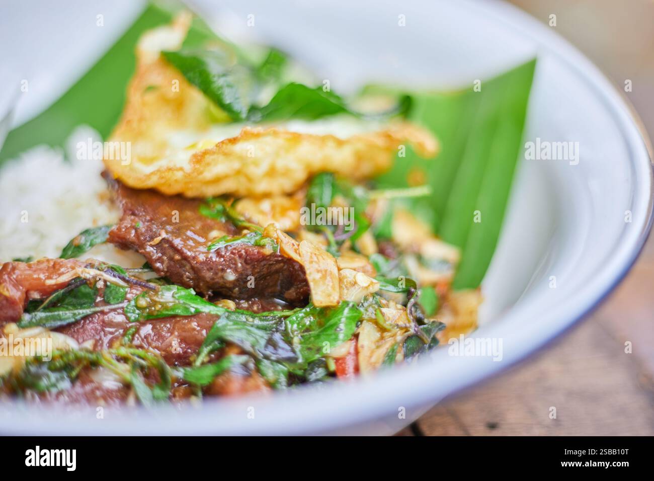 Pad Kra Pao. Frittura in padella di manzo di basilico in stile tailandese con uova fritte. Menu di piatti thailandesi Foto Stock
