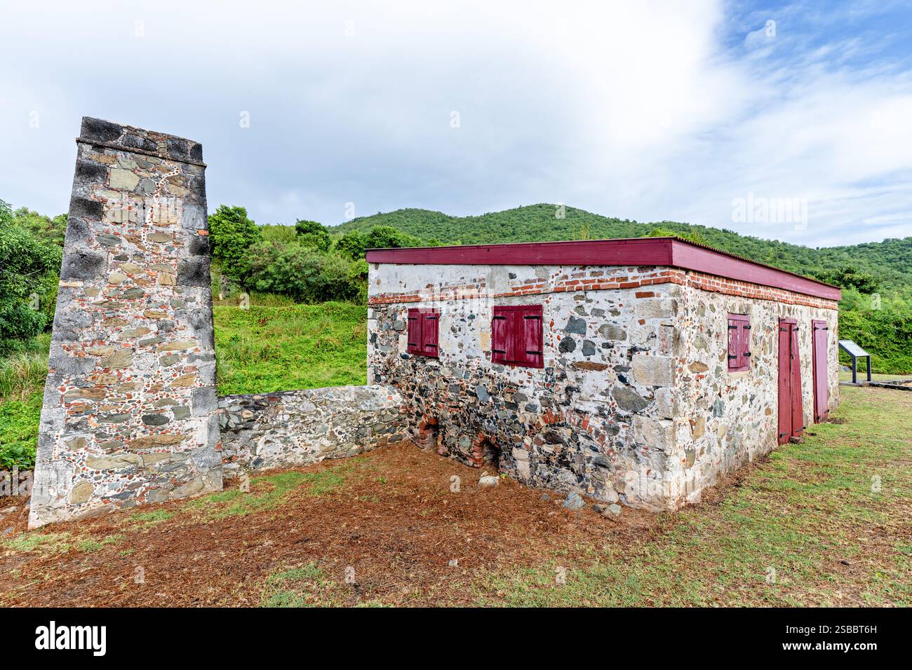 Rovine della Fabbrica di Zucchero George Francis St John Isole Vergini Americane | ST. JOHN, Isole Vergini Americane — Un camino autonomo e il guscio in pietra senza tetto della fabbrica di zucchero Francis Bay del 1874 si trovano insieme sull'istmo vicino a Mary's Creek. George Francis, precedentemente schiavizzato sulla piantagione adiacente di Annaberg, costruì il complesso dopo aver acquistato Annaberg e Leinster Bay all'indomani dei disastri del 1867 che rovinarono le piantagioni di zucchero dell'isola. Fu l'ultima fabbrica di zucchero costruita sulle terre di Annaberg. Foto Stock