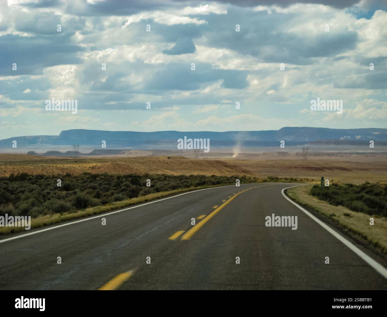 Una strada con una linea gialla nel mezzo. Il cielo è nuvoloso e la strada è vuota Foto Stock