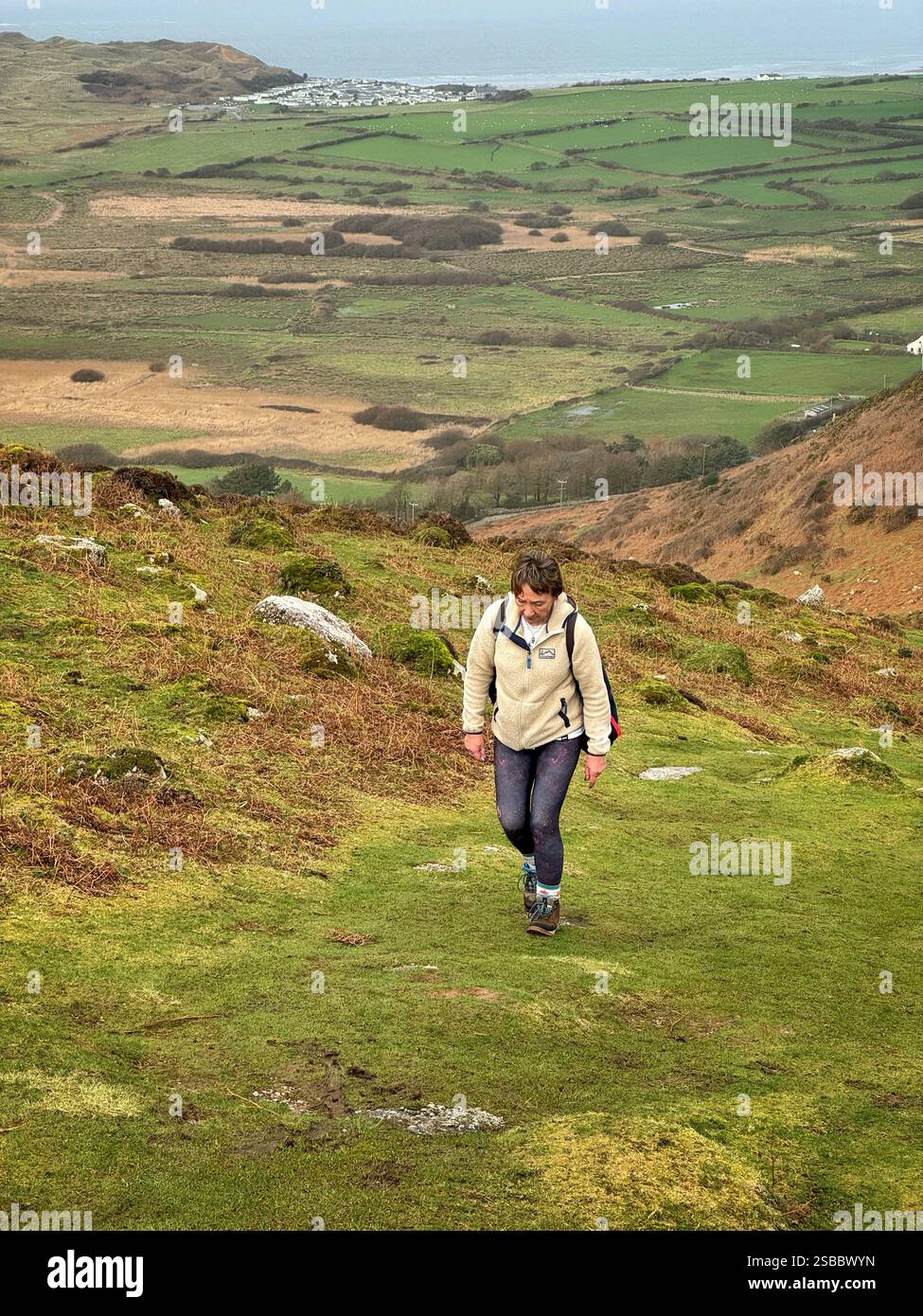 Donna che cammina sopra Rhossili Downs, sopra la spiaggia di Llangennith, Swansea, Gower, Galles sud-occidentale. Foto Stock