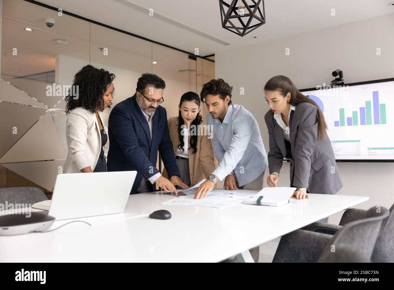 Team aziendale eterogeneo composto da colleghi seri che analizzano i report finanziari Foto Stock