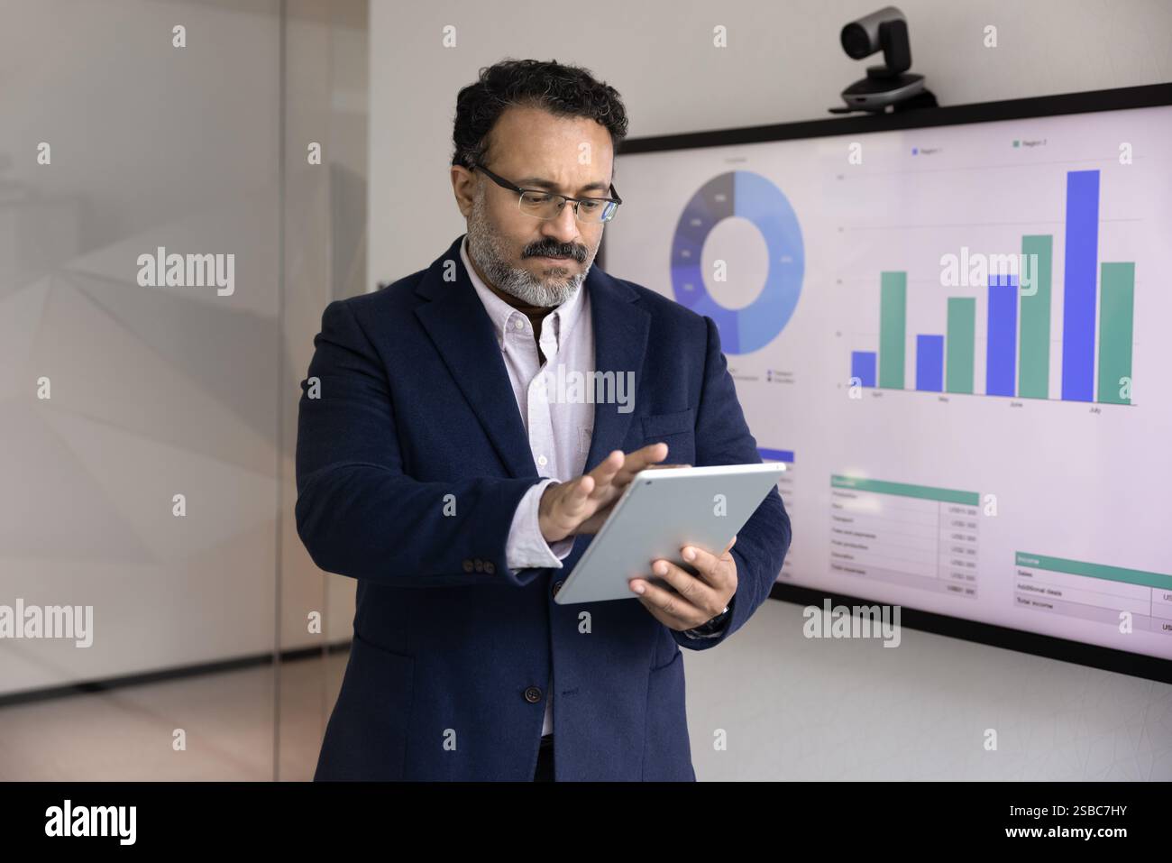 Un uomo serio, senior business leader indiano, che analizza i dati di marketing Foto Stock