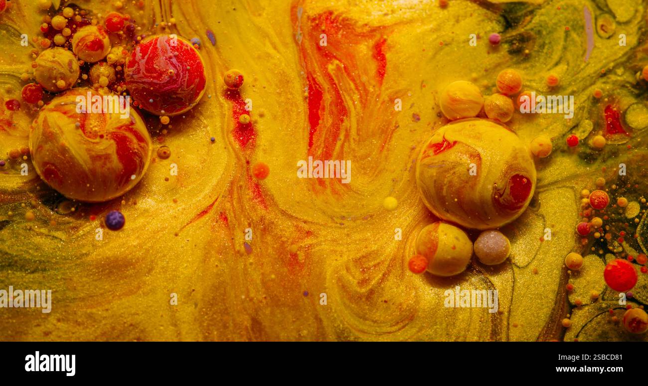 Batuffolo di vernice. Scoppia la bolla. Il colorato fa cadere le particelle che fuoriescono in acqua. Pigmento giallo rosso olio frizzante che esplode sullo sfondo astratto. Foto Stock