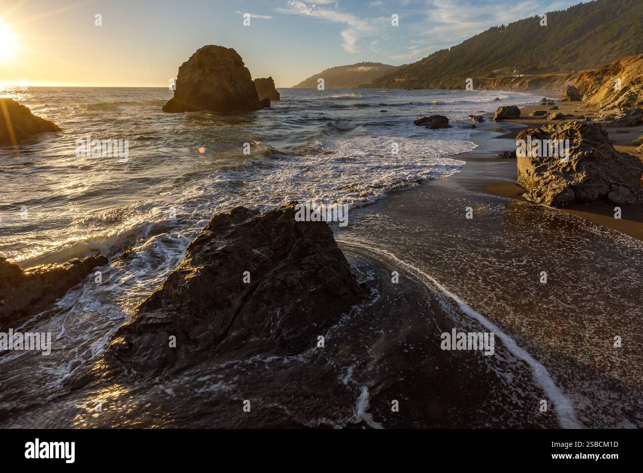 Tramonto sulla spiaggia rocciosa della costa Foto Stock