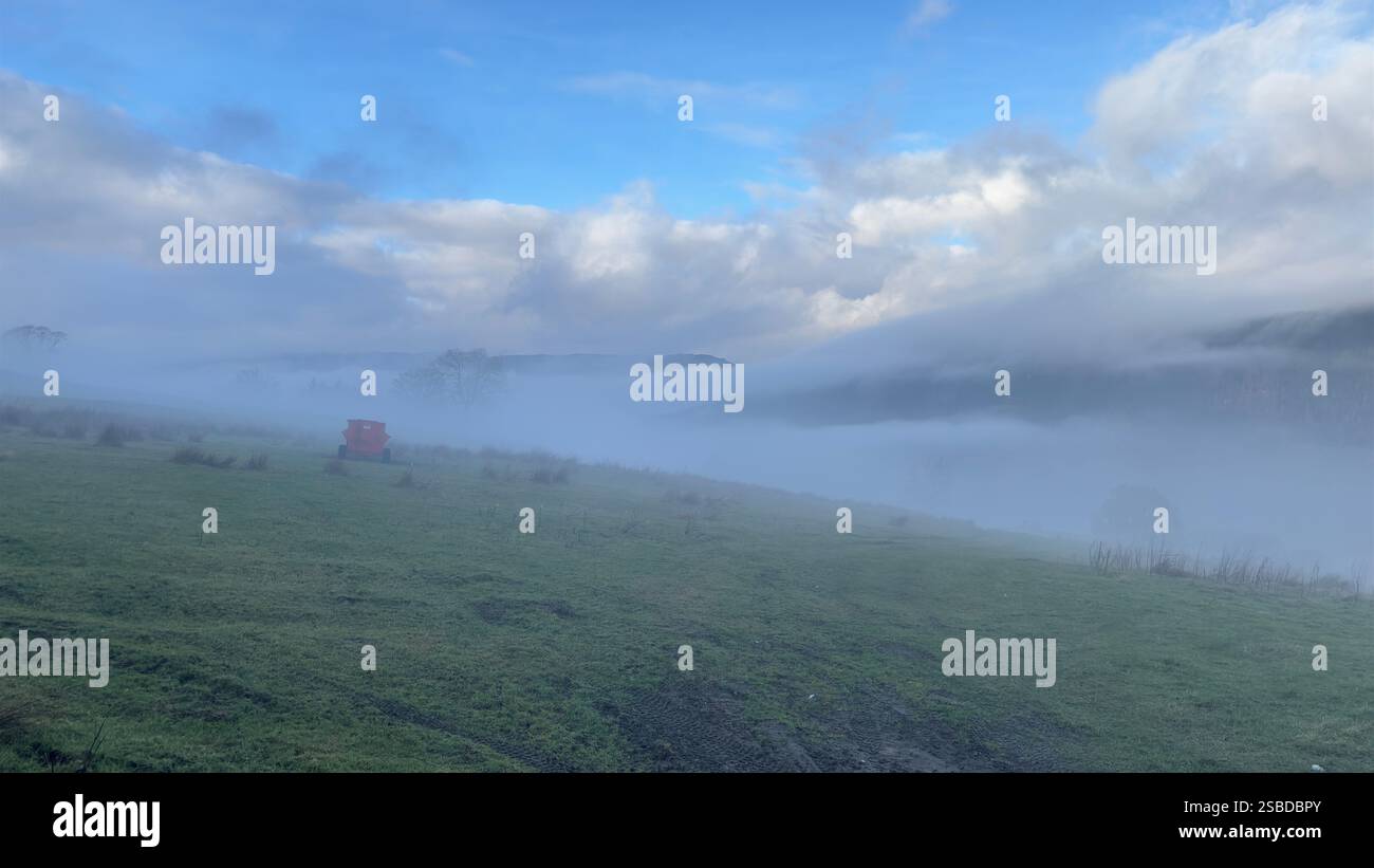 Paesaggio collinare scozzese nebbioso con macchina agricola nella nebbia. Scena spettrale - Immagine stock catturata con smartphone