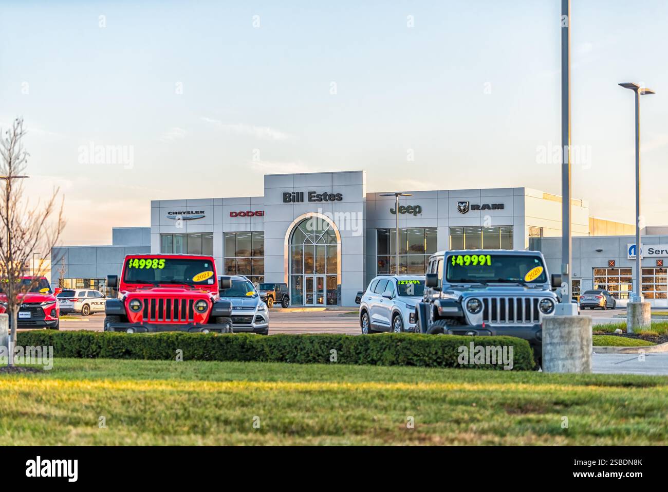 Brownsburg, Stati Uniti - 2 novembre 2022: Tramonto nel Midwest Indiana e cartello per la concessionaria Bill Estes in città con auto parcheggiate Foto Stock Brownsburg, Stati Uniti - 2 novembre 2022: Tramonto nel Midwest Indiana e cartello per la concessionaria Bill Estes in città con auto parcheggiate Foto Stock
