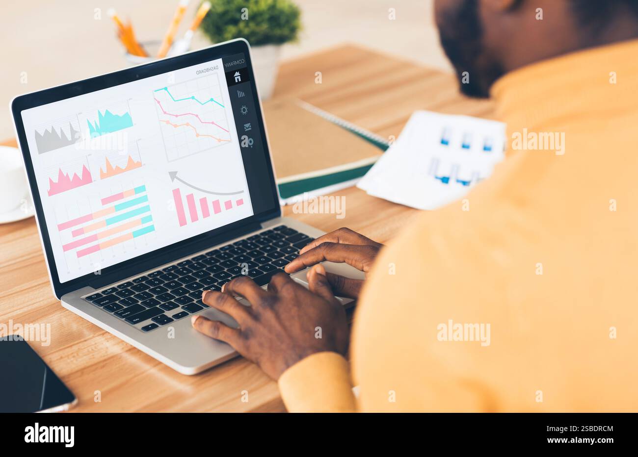Imprenditore nero che analizza il grafico sul notebook sul luogo di lavoro Foto Stock